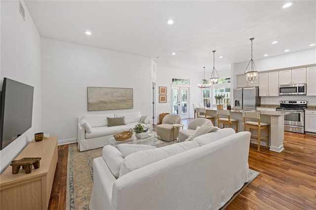 living area with baseboards, visible vents, wood finished floors, and recessed lighting