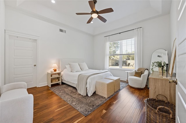 bedroom featuring baseboards, a tray ceiling, visible vents, and wood finished floors