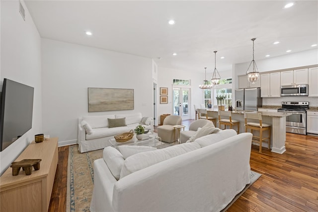 living area featuring an inviting chandelier, wood finished floors, visible vents, and recessed lighting