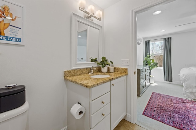 half bathroom featuring baseboards, vanity, recessed lighting, and toilet