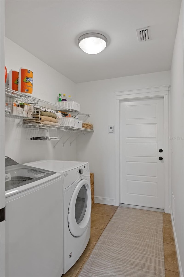laundry room with washing machine and clothes dryer, baseboards, visible vents, laundry area, and light tile patterned floors