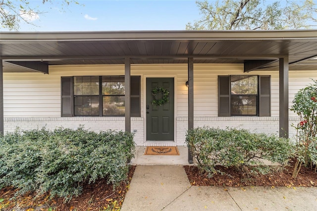 entrance to property with brick siding and a porch