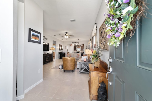 foyer featuring light tile patterned floors, ceiling fan with notable chandelier, visible vents, and baseboards