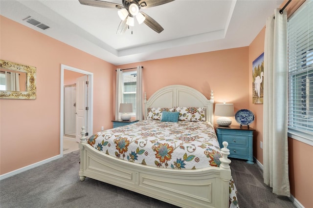 bedroom featuring dark colored carpet, visible vents, a raised ceiling, and baseboards