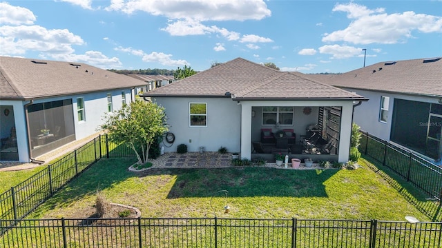 rear view of property featuring a lawn, a sunroom, a fenced backyard, and stucco siding