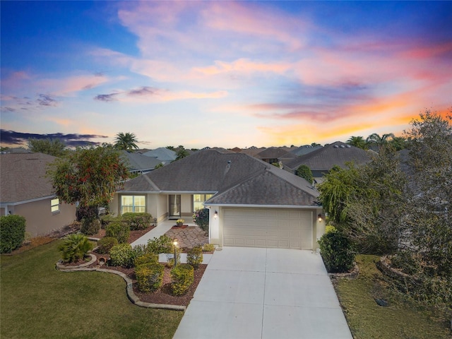 ranch-style home with roof with shingles, an attached garage, a yard, stucco siding, and concrete driveway