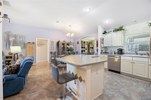 kitchen featuring visible vents, lofted ceiling, arched walkways, stainless steel dishwasher, and a kitchen bar