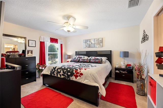 bedroom featuring visible vents, carpet flooring, a textured ceiling, and a ceiling fan