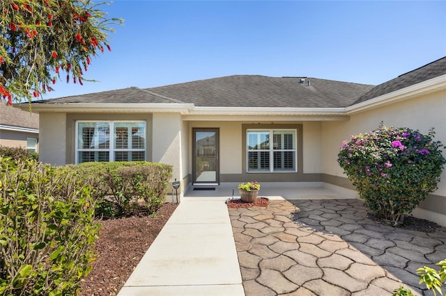 property entrance with roof with shingles and stucco siding