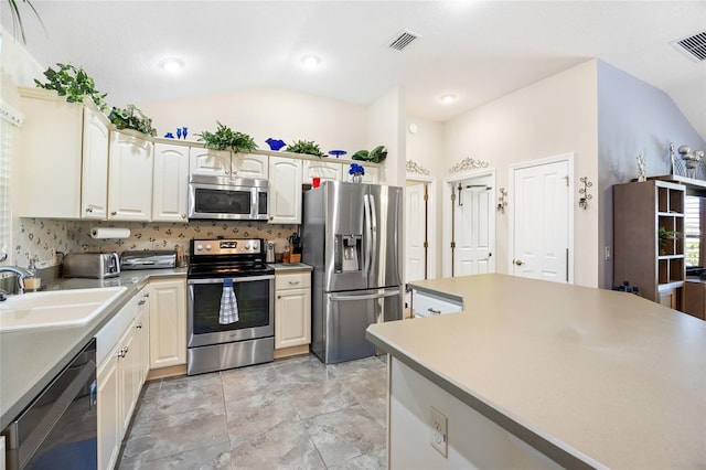 kitchen with vaulted ceiling, visible vents, stainless steel appliances, and a sink