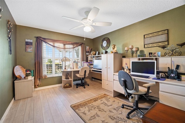 office with a textured ceiling, light wood-style flooring, baseboards, and ceiling fan