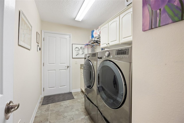 clothes washing area with baseboards, cabinet space, a textured ceiling, and independent washer and dryer