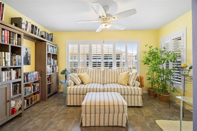 sitting room with a textured ceiling, baseboards, and a ceiling fan