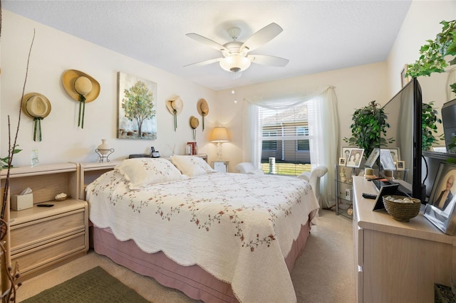 bedroom with a textured ceiling, light colored carpet, and ceiling fan