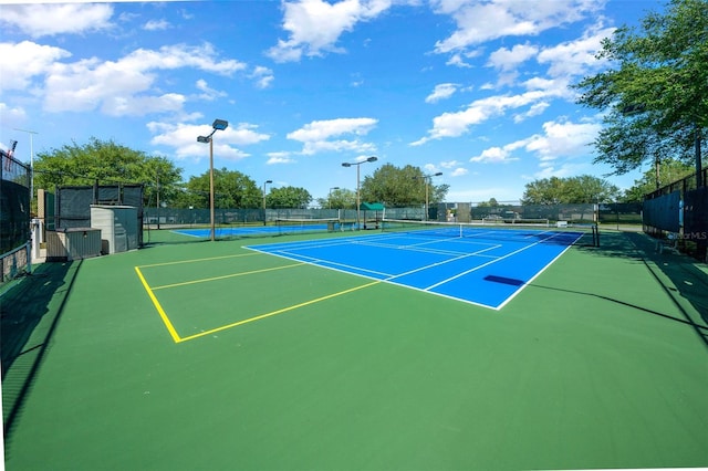 view of tennis court with community basketball court and fence