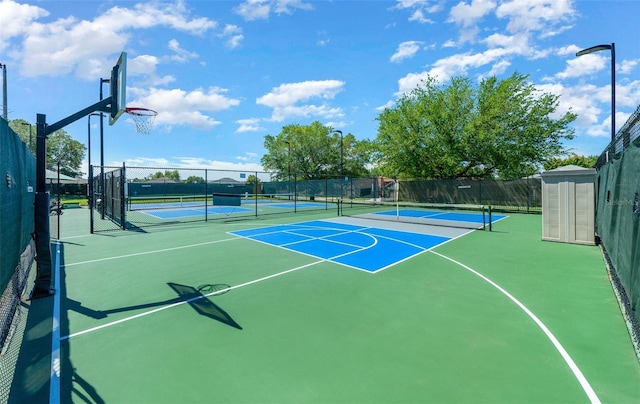 view of sport court featuring a tennis court, community basketball court, and fence