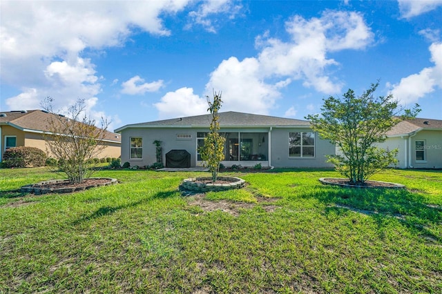 back of house featuring a lawn, a sunroom, and stucco siding