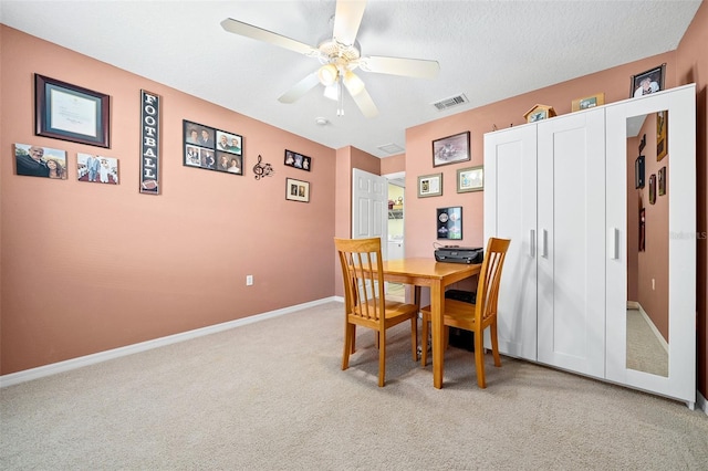 dining area featuring visible vents, a ceiling fan, a textured ceiling, baseboards, and light colored carpet