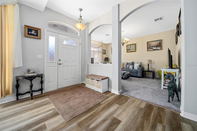 entrance foyer with wood finished floors, arched walkways, visible vents, and baseboards