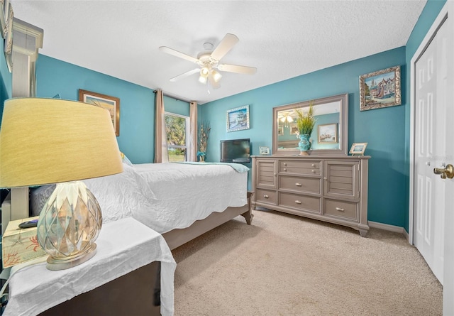 carpeted bedroom with a ceiling fan, a closet, and a textured ceiling