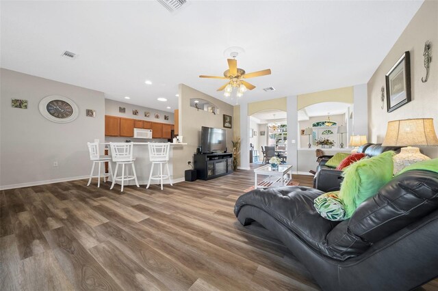 living room featuring visible vents, wood finished floors, arched walkways, and baseboards