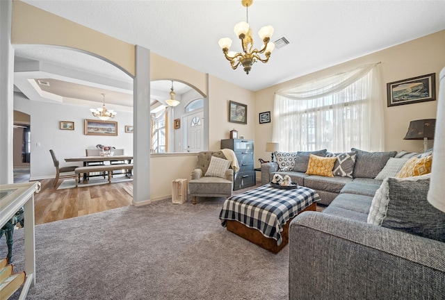 carpeted living room featuring visible vents, arched walkways, baseboards, and a chandelier