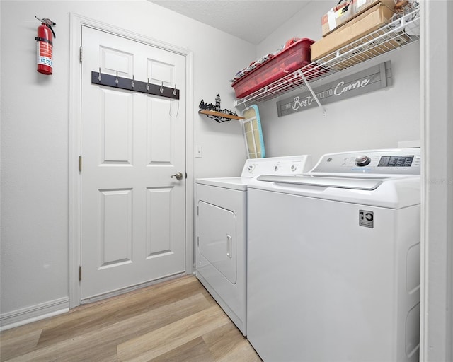 washroom with laundry area, washing machine and dryer, and light wood finished floors