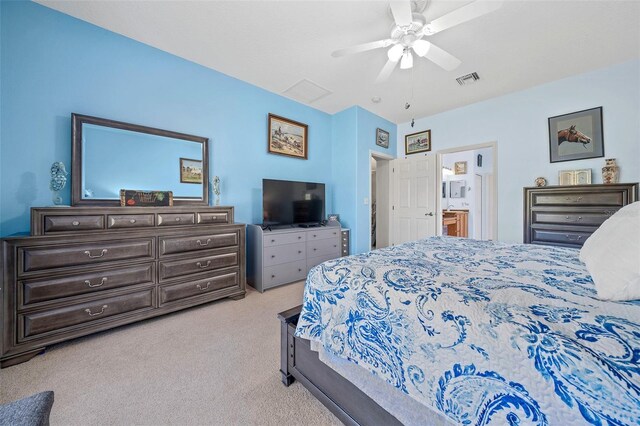 bedroom featuring ceiling fan, visible vents, ensuite bathroom, and light carpet