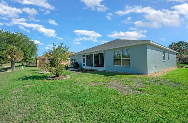 rear view of house featuring a lawn and stucco siding