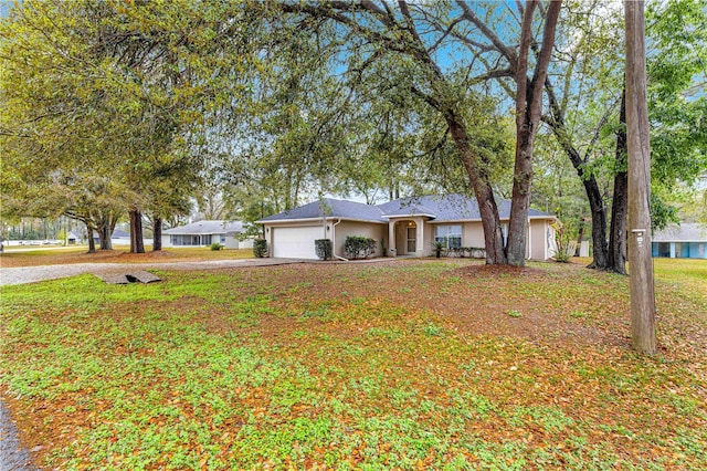 ranch-style house with a front lawn, an attached garage, driveway, and stucco siding