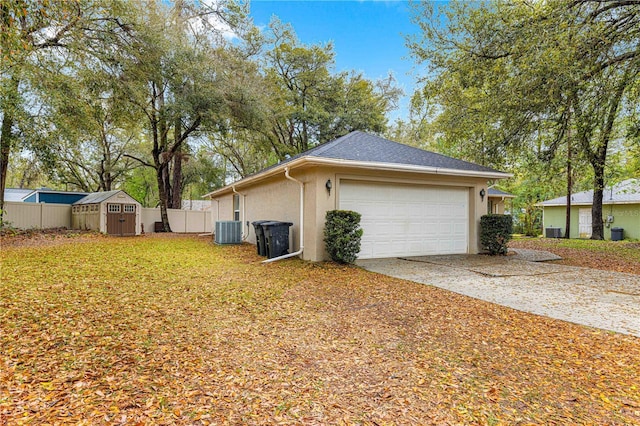 view of property exterior with fence, central air condition unit, concrete driveway, stucco siding, and an outbuilding