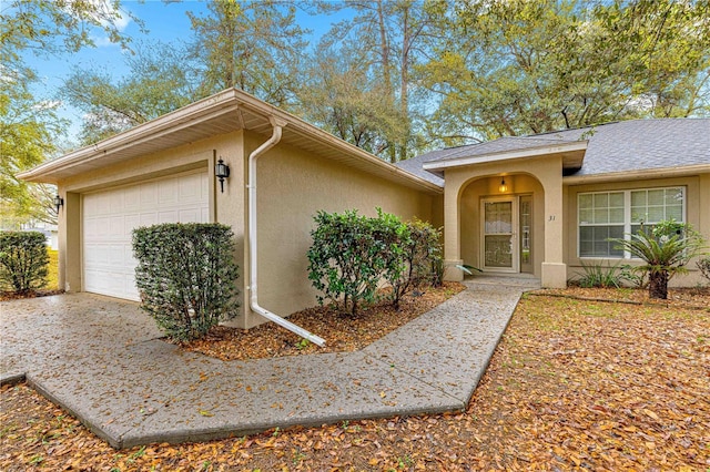 ranch-style house featuring stucco siding, driveway, roof with shingles, and an attached garage