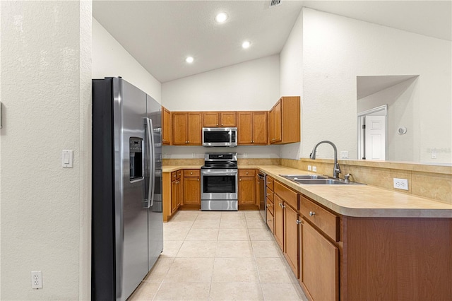 kitchen featuring brown cabinets, stainless steel appliances, light countertops, and a sink