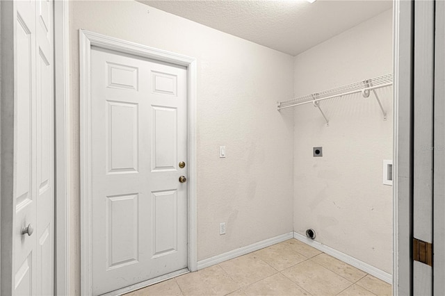 clothes washing area featuring electric dryer hookup, a textured ceiling, light tile patterned floors, baseboards, and laundry area