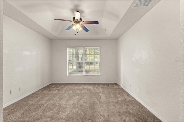 carpeted spare room featuring visible vents, a raised ceiling, baseboards, and a textured wall