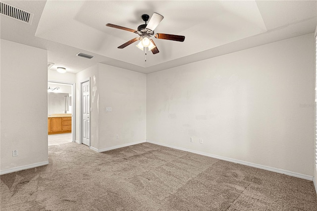 empty room featuring visible vents, light colored carpet, a ceiling fan, and baseboards