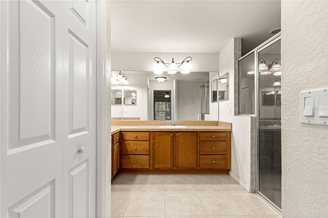 bathroom featuring a textured ceiling, vanity, a shower stall, and tile patterned flooring