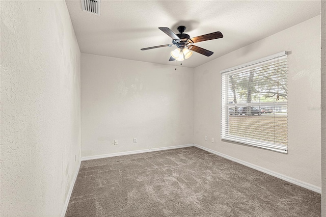 unfurnished room with visible vents, baseboards, carpet, and a textured wall