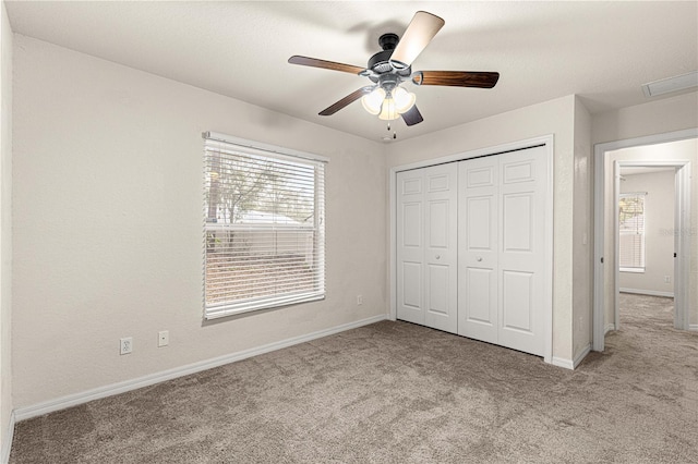 unfurnished bedroom featuring a closet, multiple windows, carpet, and baseboards