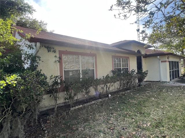 view of property exterior featuring stucco siding, a garage, and a yard