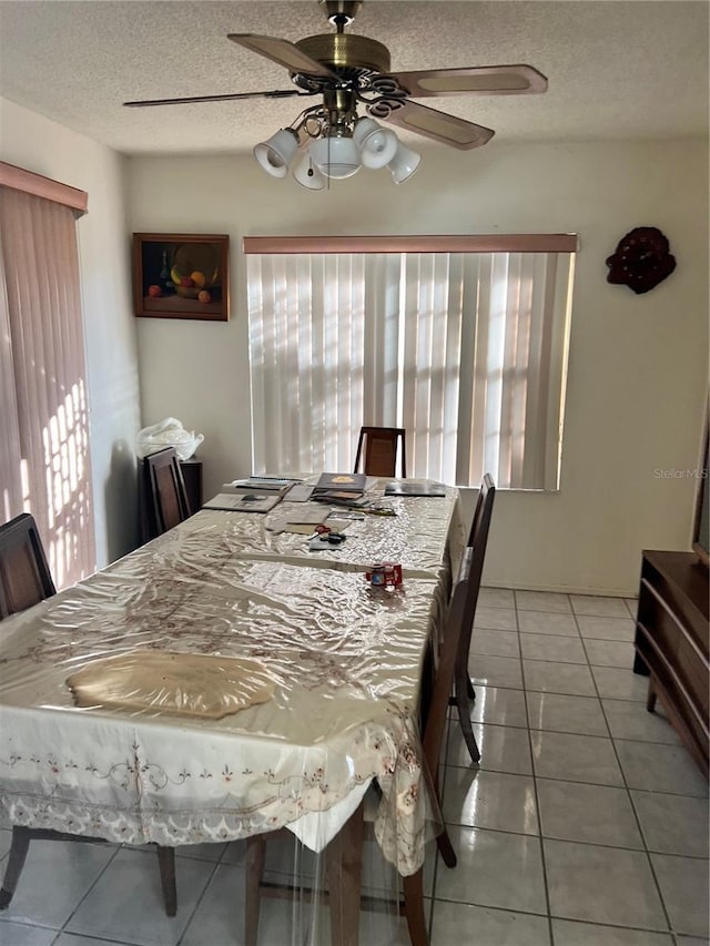 dining room featuring light tile patterned floors, a textured ceiling, a healthy amount of sunlight, and a ceiling fan