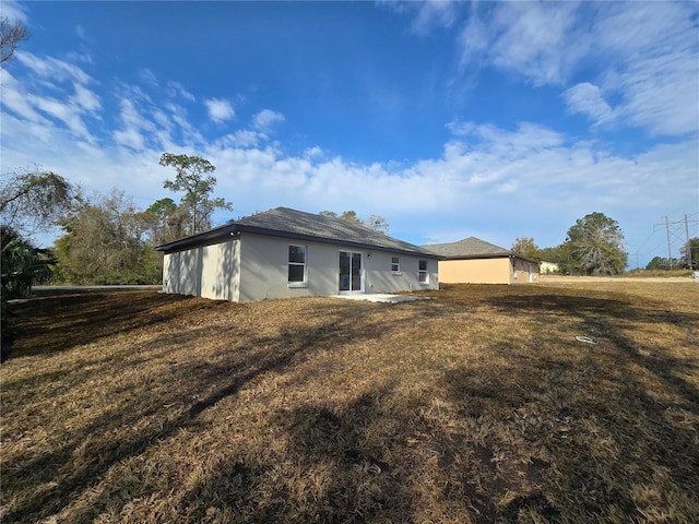 rear view of property featuring stucco siding and a lawn