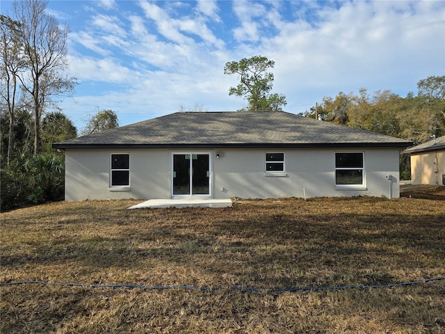 back of house featuring stucco siding, a lawn, and a patio area