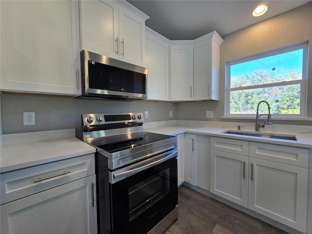 kitchen featuring white cabinetry, stainless steel appliances, light countertops, and a sink