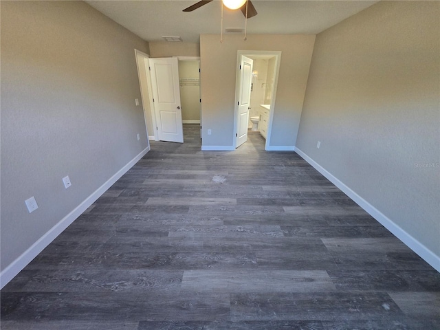 unfurnished bedroom featuring dark wood finished floors, visible vents, ensuite bath, and baseboards