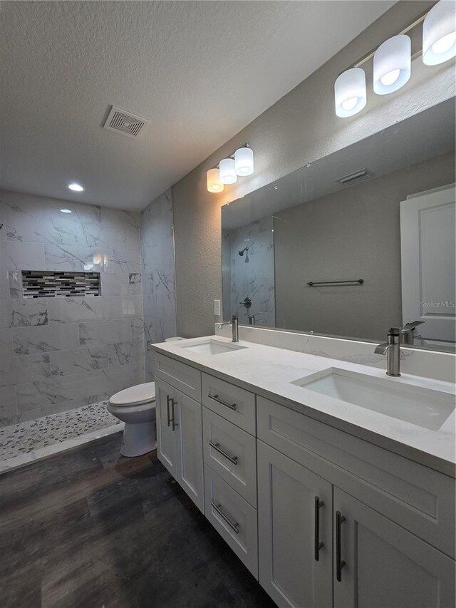 full bathroom featuring visible vents, a textured ceiling, wood finished floors, and a sink