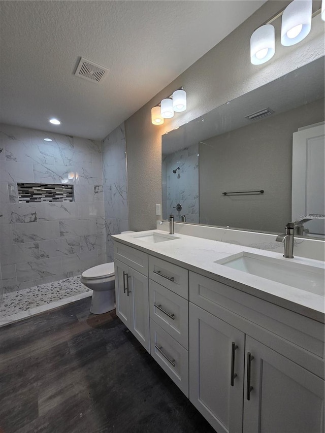 full bathroom with visible vents, a textured ceiling, wood finished floors, and a sink