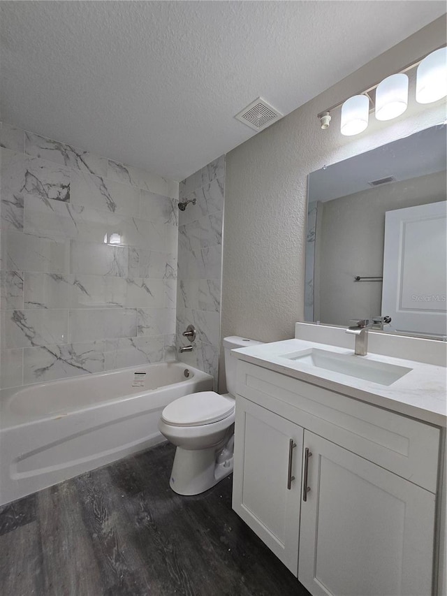 bathroom featuring toilet, shower / bath combination, a textured wall, wood finished floors, and a textured ceiling