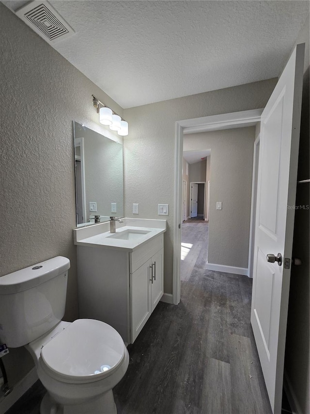 bathroom with visible vents, wood finished floors, vanity, and a textured wall