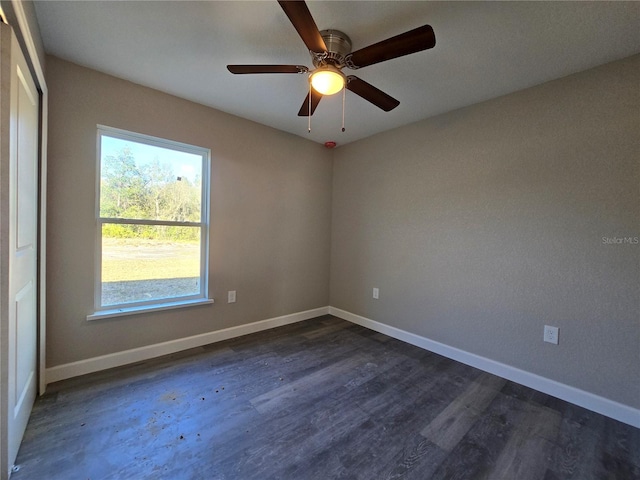 empty room with a ceiling fan, baseboards, and dark wood-style flooring